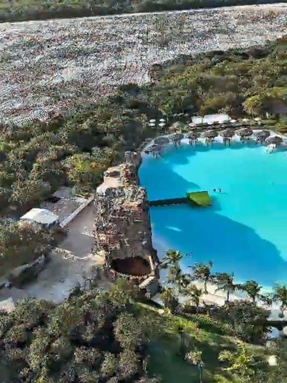 Vista aérea de uma lagoa azul-turquesa cercada de coqueiros em Jericoacoara