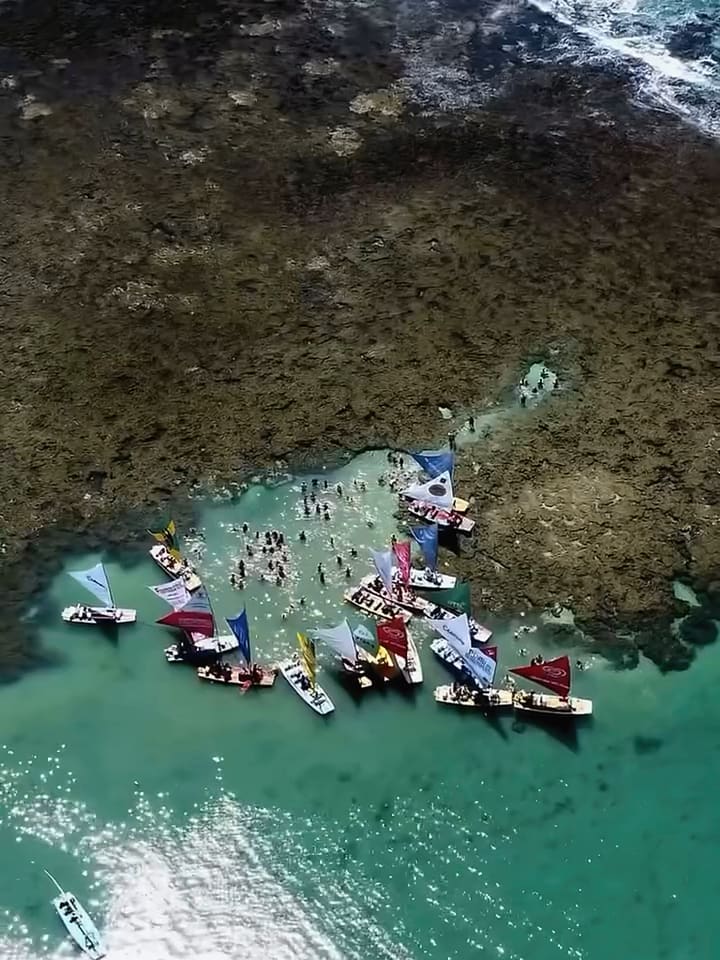 Vista aérea das piscinas naturais de Porto de Galinhas, com jangadas sobre os recifes